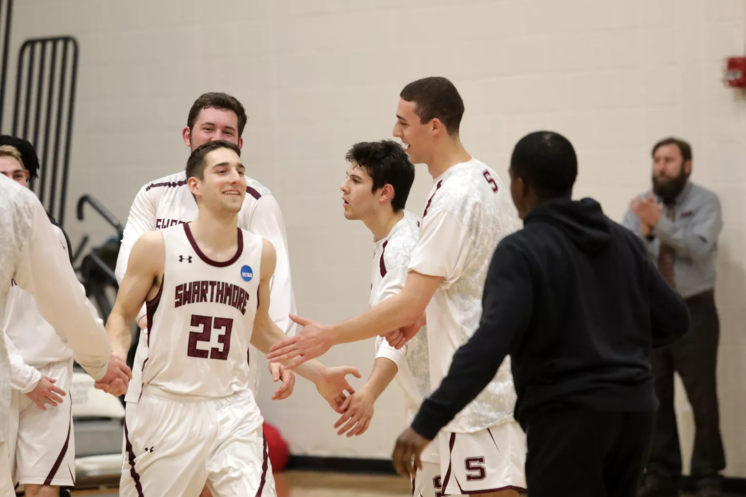 Student in white jersey receives high fives from teammates