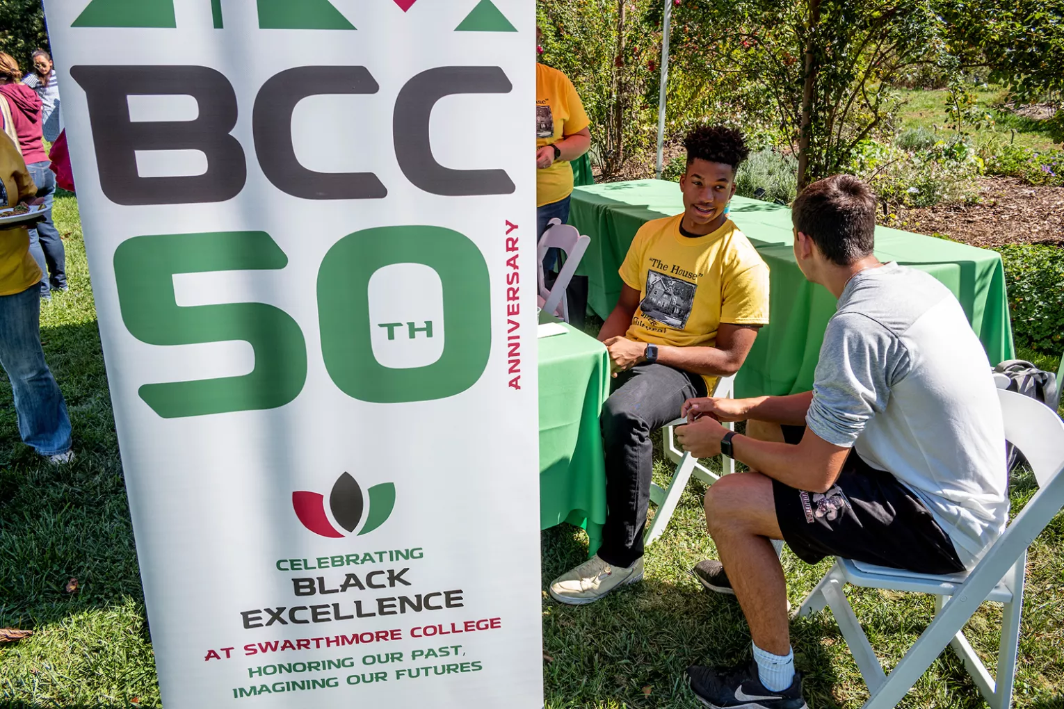 Student sits near sign that reads "BCC 50th Anniversary"