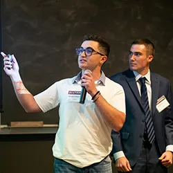 Student with microphone points to blackboard