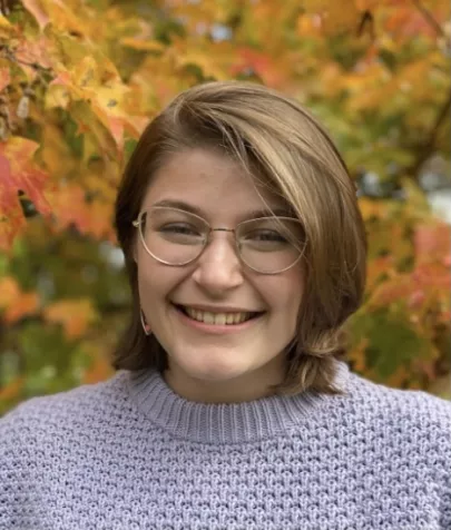 Michele smiling in front of fall leaves