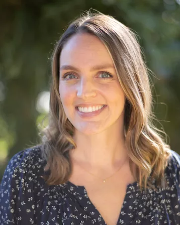 Photo of female-presenting person with trees in backdrop