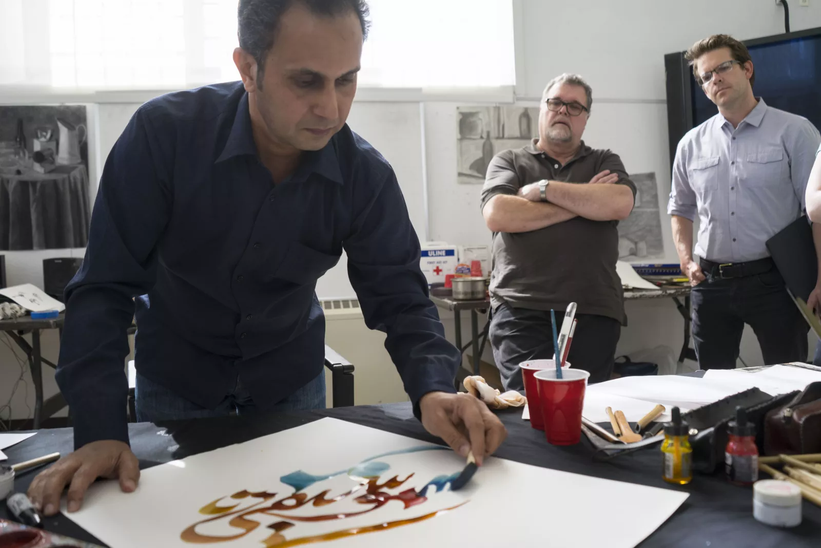 Faculty watch as Khaled al-Saai provides calligraphy demo