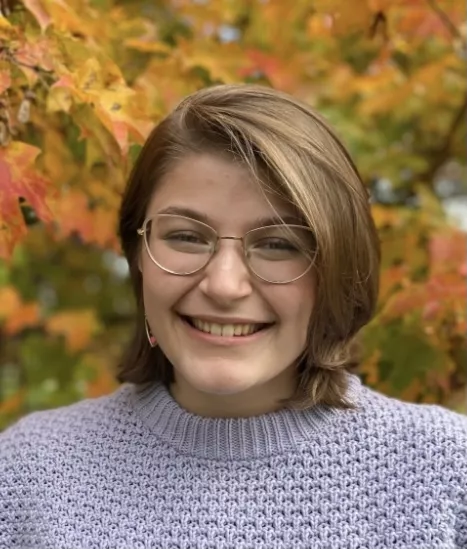 Michele smiling in front of fall leaves