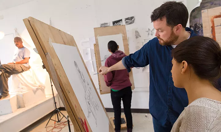 An instructor advises a student on her drawing