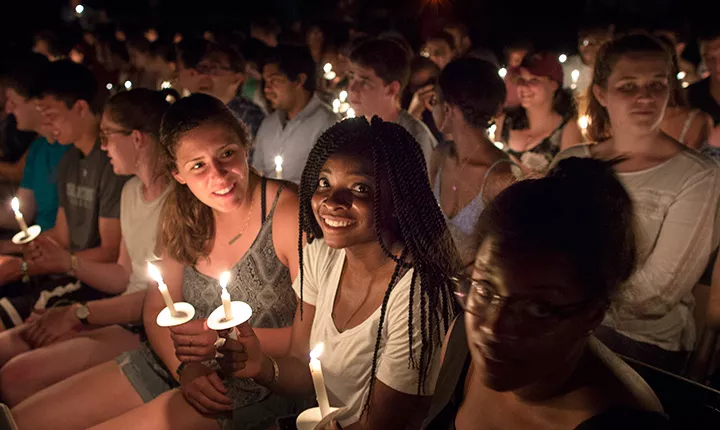 Students sit with their candles