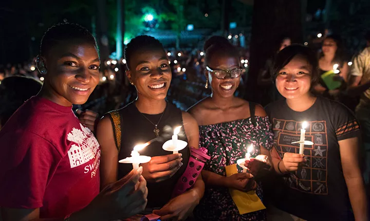 Four students stand with their candles.