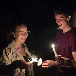 two students lighting candles at first collection