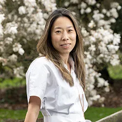 Roseann Liu sits outside in front of blooming tree